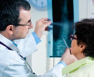 radiologist with technologist, holding up and pointing to a detail of an x-ray