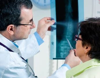 radiologist with technologist, holding up and pointing to a detail of an x-ray
