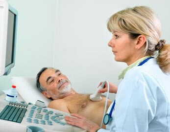 Female cardiovascular technician takes ultrasound of male patient's heart