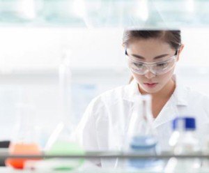 Medical lab technologist, seen from between shelves of beakers and vials