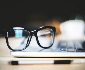 detail of eyeglasses resting on a laptop