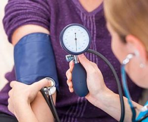 Detail of medical assistant checking patient blood pressure
